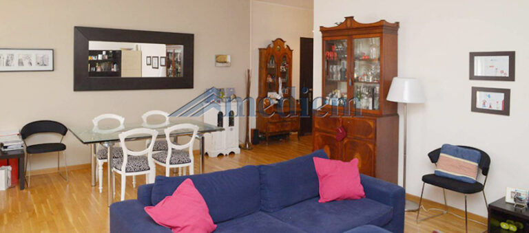 Soggiorno arredato con divano blu, tavolo da pranzo e credenza in un appartamento a Milano