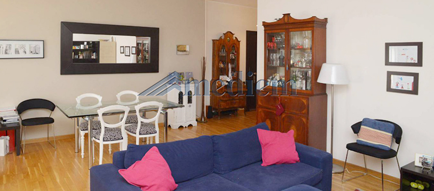 Soggiorno arredato con divano blu, tavolo da pranzo e credenza in un appartamento a Milano