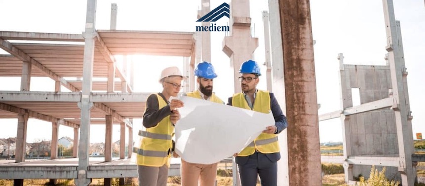 Tecnici con elmetto esaminano i disegni strutturali in un cantiere: verifica dell'idoneità statica di un edificio a Milano